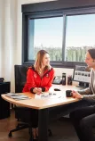 A customer and a saleswoman discuss at a desk the evolutions on Renault Trucks trucks and services.